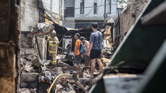 Petugas pemadam kebakaran bersama warga melakukan proses pendinginan pada salah satu bangunan pascakebakaran yang melanda kawasan permukiman padat penduduk di Petojo Selatan, Jakarta, Kamis (24/8/2023). [ANTARA FOTO/Muhammad Adimaja].