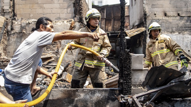 Petugas pemadam kebakaran bersama warga melakukan proses pendinginan pada salah satu bangunan pascakebakaran yang melanda kawasan permukiman padat penduduk di Petojo Selatan, Jakarta, Kamis (24/8/2023). [ANTARA FOTO/Muhammad Adimaja].