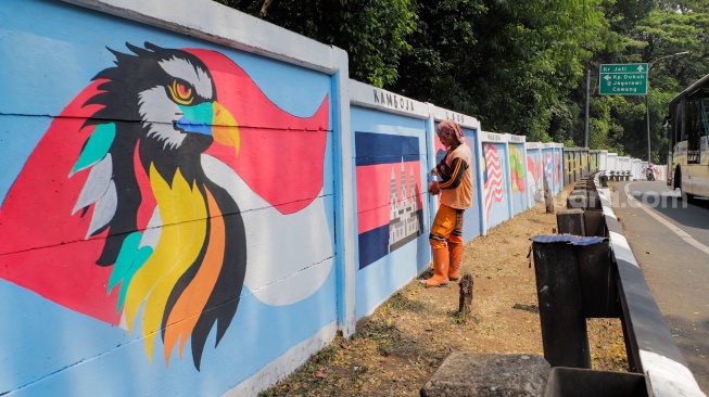 Petugas Penanganan Prasarana dan Sarana Umum (PPSU) membuat mural di Jalan Haji Bokir bin Djiun, Kramat Jati, Jakarta Timur, Kamis (24/8/2023). [Suara.com/Alfian Winanto]