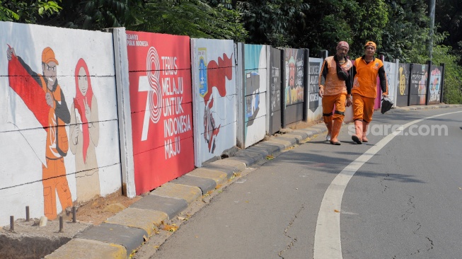 Petugas Penanganan Prasarana dan Sarana Umum (PPSU) membuat mural di Jalan Haji Bokir bin Djiun, Kramat Jati, Jakarta Timur, Kamis (24/8/2023). [Suara.com/Alfian Winanto]