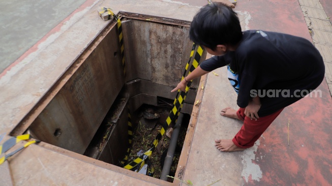 Warga menunjukkan dalamnya lubang saluran kabel di Jalan Raya Casablanca, Jakarta, Jumat (25/8/2023). [Suara.com/Alfian Winanto]