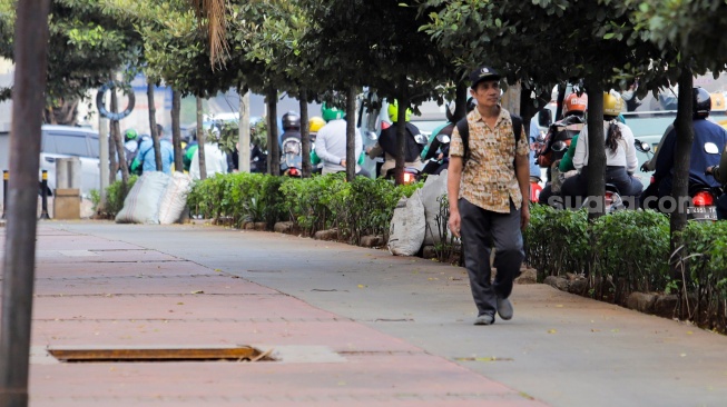 Warga berjalan menghindari lubang saluran kabel di Jalan Raya Casablanca, Jakarta, Jumat (25/8/2023). [Suara.com/Alfian Winanto]