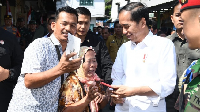 Presiden Joko Widodo atau Jokowi tersenyum melihat seorang ibu yang menangis usai berfoto bersama di Pasar Brahrang, Kota Binjai, Sumatera Utara pada Jumat (25/8/2023). (Kris - Biro Pers Sekretariat Presiden)