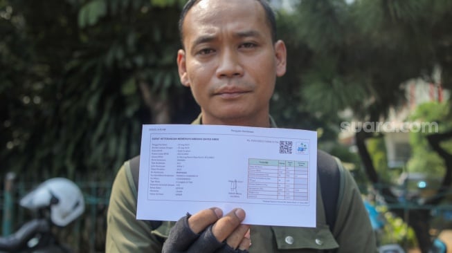 Pengendara menunjukkan hasil uji emisi kendaraan bermotor di Terminal Blok M, Jakarta Selatan, Jumat (25/8/2023). [Suara.com/Alfian Winanto]