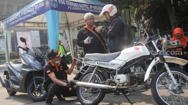 Petugas melakukan uji emisi kendaraan bermotor di Terminal Blok M, Jakarta Selatan, Jumat (25/8/2023). [Suara.com/Alfian Winanto]