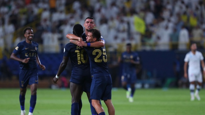 Penyerang Al Nassr, Cristiano Ronaldo (tengah) memeluk dua rekannya usai mencetak gol ke gawang Al Shabab dalam laga lanjutan Liga Arab Saudi 2023-2024 di Stadion Al Awal Park, Riyadh, Arab Saudi, Rabu (30/8/2023). [Twitter/@AlNassrFC_EN]