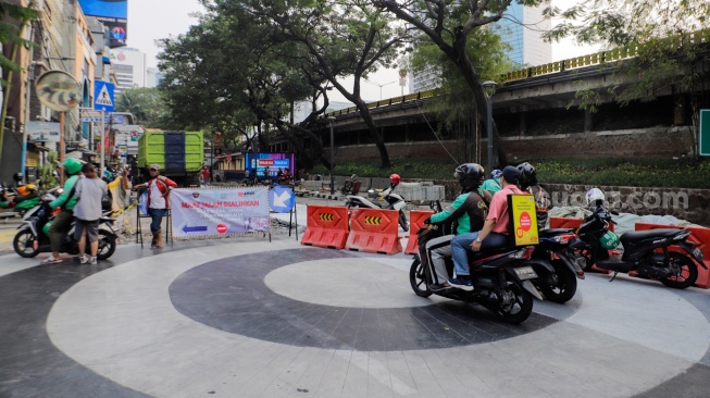 Pengemudi ojek online melintas di Jalan Blora, Jakarta Pusat, Kamis (31/8/2023). [Suara.com/Alfian Winanto]