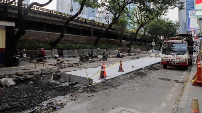 Pekerja menyelesaikan proyek pembangunan jalur pedestrian di Jalan Blora, Jakarta Pusat, Kamis (31/8/2023). [Suara.com/Alfian Winanto]