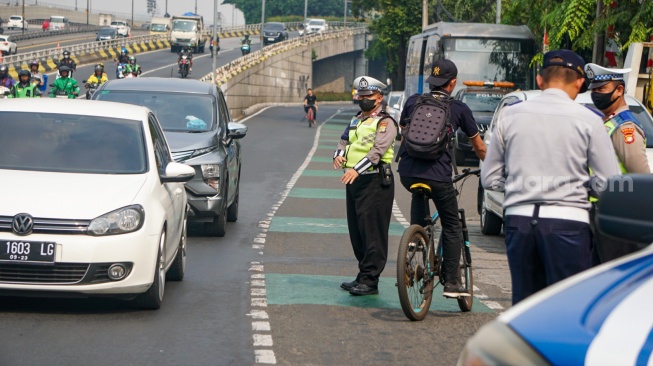 Polisi memberikan pengarahan kepada pengendara mobil yang akan melakukan uji emisi di Subdit Gakkum Ditlantas Polda Metro Jaya, Jakarta, Jumat (1/9/2023). [Suara.com/Alfian Winanto]