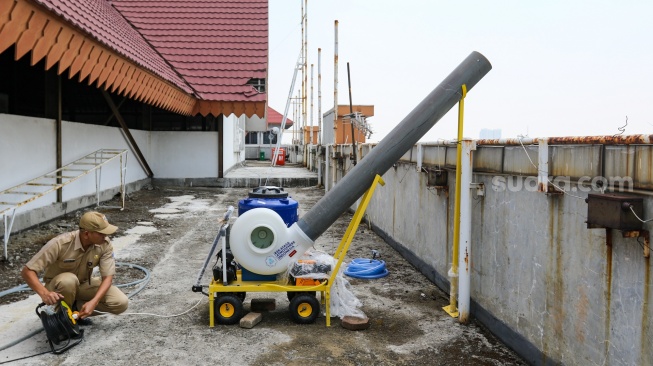 Petugas mengoperasikan alat penyemprot kabut udara (water sprayer) yang terpasang di atap Gedung Kantor Wali Kota Jakarta Pusat, Jumat (8/9/2023). [Suara.com/Alfian Winanto]