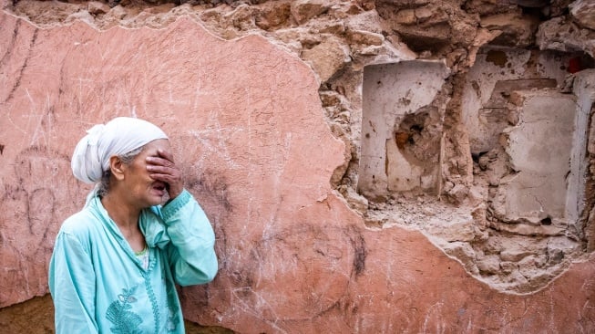 Seorang wanita bersedih di depan rumahnya yang rusak akibat gempa di kota tua Marrakesh, Maroko, Sabtu (9/9/2023). [FADEL SENNA / AFP]