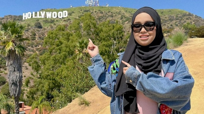 Putri Ariani menunjuk bukit Hollywood yang menjadi landmark kota Los Angeles. [Instagram]