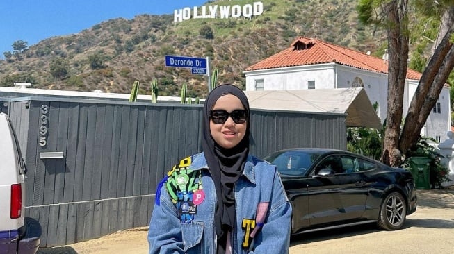 Putri Ariani berpose dengan latar belakang bukit bertuliskan Hollywood di Los Angeles. [Instagram]