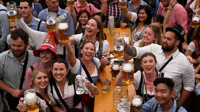 Orang-orang merayakan pembukaan festival Oktoberfest 2023 di Munich, Jerman, Sabtu (16/9/2023). [Christof STACHE / AFP]