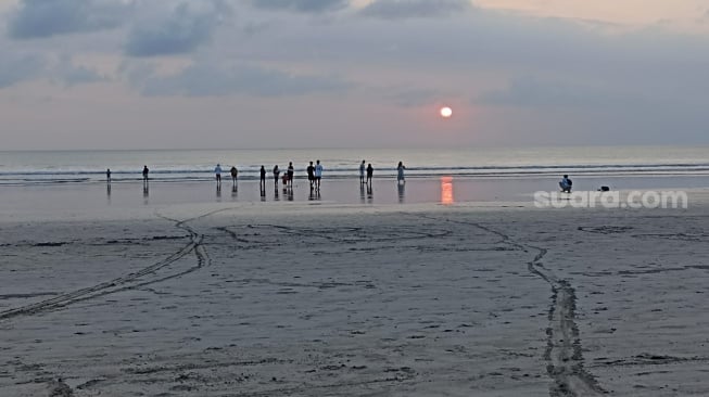 Wisatawan menikmati matahari terbenam di Pantai Kuta, Bali, Selasa (19/9/2023) [Suara.com / Eviera Paramita Sandi] 