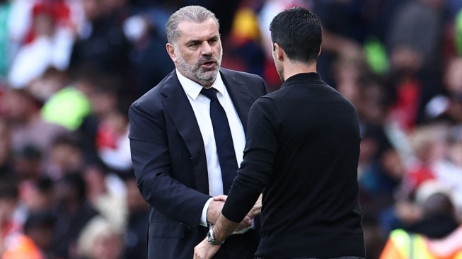 Pelatih Tottenham Hotspur, Ange Postecoglou (kiri) berjabat tangan dengan manajer Arsenal, Mikel Arteta pada laga Liga Inggris di Stadion Emirates, London, Minggu (24/9) malam WIB. [HENRY NICHOLLS / AFP]