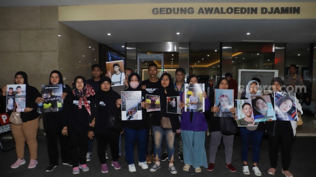 Keluarga Korban Tragedi Kanjuruhan menunjukkan poster berisi foto keluarga mereka yang menjadi korban saat mendatangi Bareskrim Mabes Polri, Jakarta, Rabu (27/9/2023). [Suara.com/Alfian Winanto]