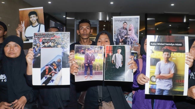 Keluarga Korban Tragedi Kanjuruhan menunjukkan poster berisi foto keluarga mereka yang menjadi korban saat mendatangi Bareskrim Mabes Polri, Jakarta, Rabu (27/9/2023). [Suara.com/Alfian Winanto]