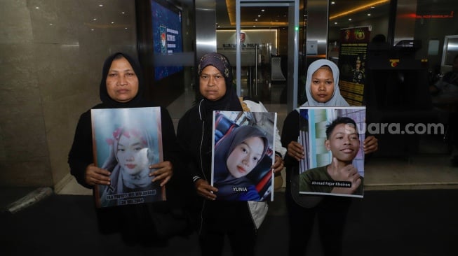 Keluarga Korban Tragedi Kanjuruhan menunjukkan poster berisi foto keluarga mereka yang menjadi korban saat mendatangi Bareskrim Mabes Polri, Jakarta, Rabu (27/9/2023). [Suara.com/Alfian Winanto]