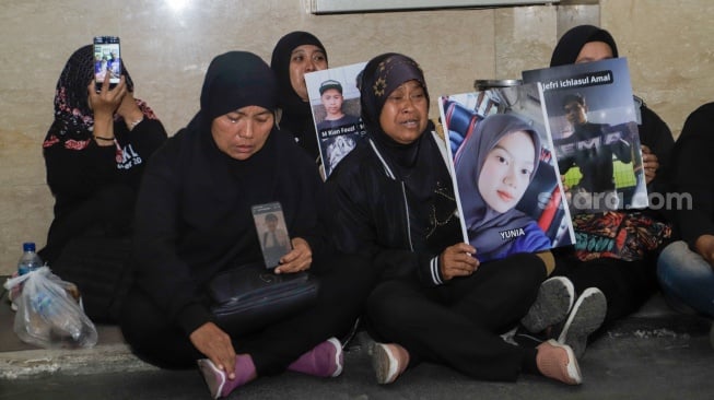 Keluarga Korban Tragedi Kanjuruhan menunjukkan poster berisi foto keluarga mereka yang menjadi korban saat mendatangi Bareskrim Mabes Polri, Jakarta, Rabu (27/9/2023). [Suara.com/Alfian Winanto]