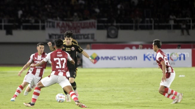 Gelandang Persija Jakarta, Ryo Matsumura dibayangi tiga pemain Persis dalam laga lanjutan pekan ke-14 BRI Liga 1 2023/2024 di Stadion Manahan, Sabtu (30/9/2023). [Suara.com/Ronald Seger Prabowo]