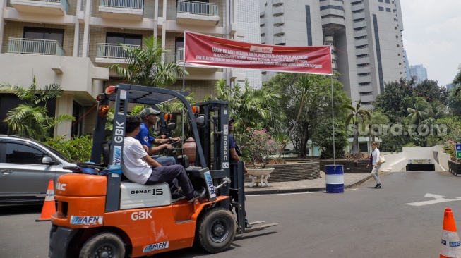 Petugas memasang spanduk peringatan di Hotel Sultan, Kompleks GBK, Jakarta, Rabu (4/10/2023). [Suara.com/Alfian Winanto]