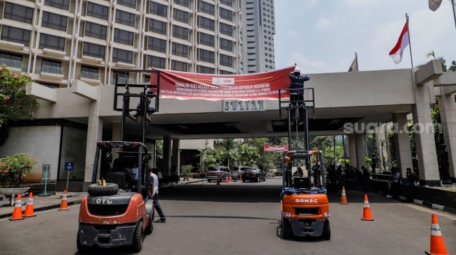 Petugas memasang spanduk peringatan di Hotel Sultan, Kompleks GBK, Jakarta, Rabu (4/10/2023). [Suara.com/Alfian Winanto]