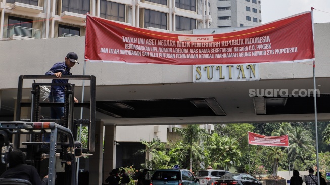 Petugas memasang spanduk peringatan di Hotel Sultan, Kompleks GBK, Jakarta, Rabu (4/10/2023). [Suara.com/Alfian Winanto]