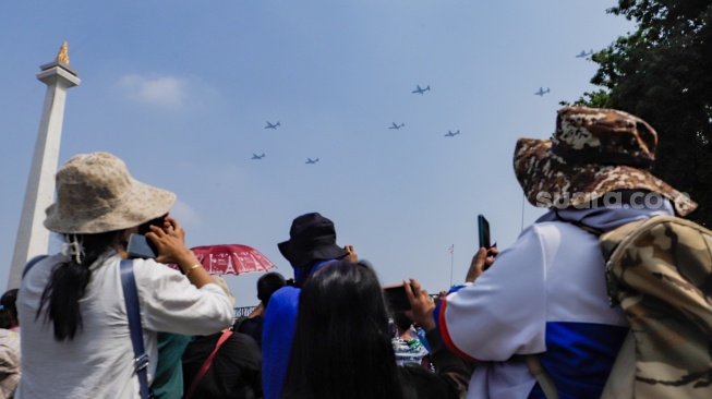 Warga melihat Atraksi udara pesawat terbang pada peringatan HUT ke-78 TNI di Lapangan Silang Monumen Nasional (Monas), Gambir, Jakarta, Kamis (5/10/2023). [Suara.com/Alfian Winanto]