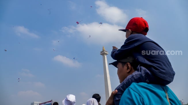 Warga melihat prajurit TNI melakukan atraksi terjun payung pada peringatan HUT ke-78 TNI di Lapangan Silang Monumen Nasional (Monas), Gambir, Jakarta, Kamis (5/10/2023). [Suara.com/Alfian Winanto]