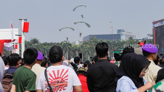 Warga melihat prajurit TNI melakukan atraksi terjun payung pada peringatan HUT ke-78 TNI di Lapangan Silang Monumen Nasional (Monas), Gambir, Jakarta, Kamis (5/10/2023). [Suara.com/Alfian Winanto]