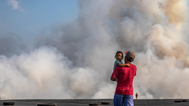 Warga menyaksikan kepulan asap yang membumbung dari tumpukan sampah yang terbakar di tempat pembuangan akhir (TPA) Jatibarang Semarang, Jawa Tengah, Jumat (6/10/2023). [ANTARA FOTO/ANTARA FOTO/Aji Styawan/tom]