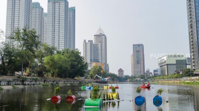 Petugas menyiram tanaman yang ada di dalam Pot Apung di Waduk Melati, Jakarta, Jumat (6/10/2023). [Suara.com/Alfian Winanto]