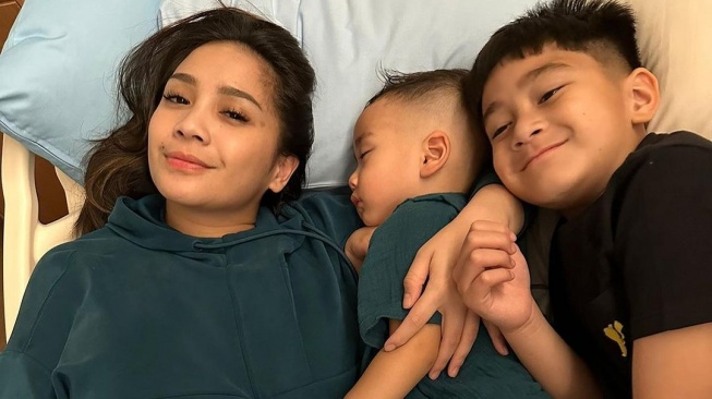 Nagita Slavina memeluk erat Rayyanza yang tengah sakit. Di sisi kanan Cipung ada juga sang kakak, Rafathar. [Instagram]