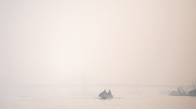 Perahu tradisional melewati sungai musi yang tertutup kabut asap di Palembang, Sumatera Selatam, Sabtu (7/10/2023). [ANTARA FOTO/Nova Wahyudi/YU]