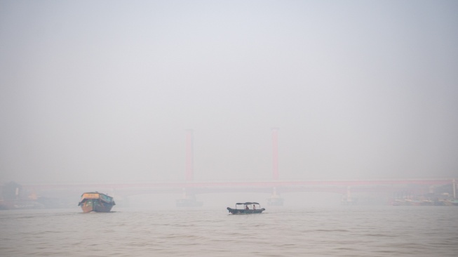 Perahu tradisional melewati sungai musi yang tertutup kabut asap di Palembang, Sumatera Selatam, Sabtu (7/10/2023). [ANTARA FOTO/Nova Wahyudi/YU]