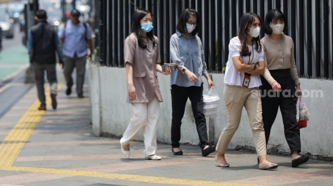 Pekerja melintasi pelican crossing di Jakarta, Senin (9/10/2023). [Suara.com/Alfian Winanto]