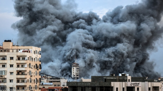 Kepulan asap membubung di atas gedung-gedung yang terkena serangan udara Israel di Kota Gaza, Palestina, Sabtu (7/10/2023). [MAHMUD HAMS / AFP]
