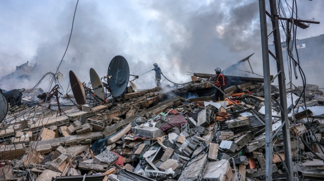 Petugas pemadam kebakaran memadamkan api di reruntuhan bangunan yang hancur akibat serangan udara Israel di Kota Gaza, Palestina, Minggu (8/10/2023). [Mohammed ABED / AFP]
