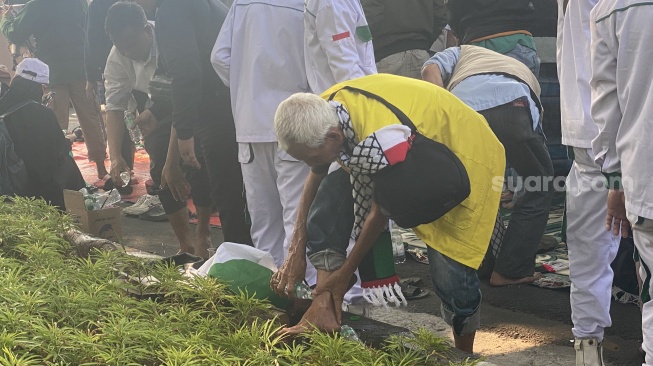 Massa aksi solidaritas Palestina menunaikan salat Ashar berjemaah di depan Kantor Kedubes Amerika Serikat, Jakarta Pusat, Rabu (11/10/2023). (Suara.com/Faqih)