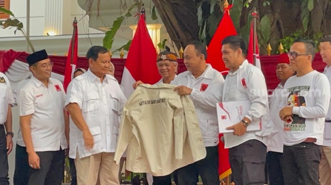 Ketua Umum Projo, Budi Arie Setiadi menyerahkan jaket krem sebagai simbol capres Prabowo Subianto menjadi anggota kehormatan di Jalan Kertanegara, Jakarta Selatan, Sabtu (14/10/2023). (Suara.com/Bagaskara)