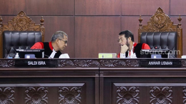 Hakim ketua Mahkamah Konstitusi Anwar Usman (kanan) berbicara dengan Wakil Ketua Mahkamah Konstitusi Saldi Isra (kiri) saat sidang penetapan batas usia Calon Presiden (Capres) dan Calon Wakil Presiden (Cawapres) di Gedung Mahkamah Konstitusi, Jakarta, Senin (16/10/2023). [Suara.com/Alfian Winanto]