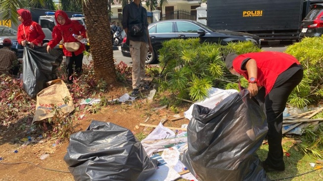 Relawan pasangan Ganjar-Mahfud gelar operasi semut berupa memungut sampah yang berserakan di depan kantor KPU RI, Jakarta Pusat, Kamis (19/10/2023) sore. [Suara.com/Rakha]