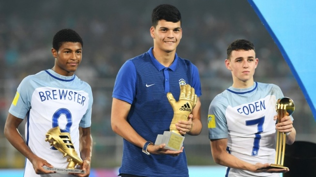 Gelandang Inggris Phil Foden (kanan) dengan trofi 'Man of the Tournament', pemain depan Inggris Rhin Brewster (kiri) dengan trofi 'Pencetak Gol Terbanyak' dan kiper Inggris asal Brazil Gabriel Brazao dengan trofi 'Kiper Terbaik' berpose untuk foto setelah pertandingan Inggris menang atas Spanyol dalam pertandingan final sepak bola Piala Dunia U-17 FIFA di stadion Vivekananda Yuba Bharati Krirangan di Kolkata pada 28 Oktober 2017.Dibyangshu SARKAR / AFP