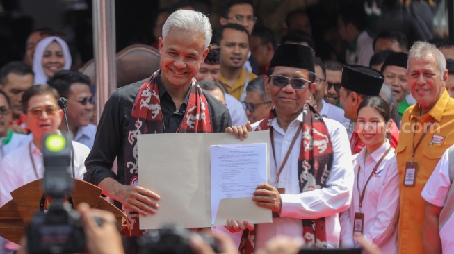 Bakal calon Presiden Ganjar Pranowo bersama dengan bakal calon Wakil Presiden Mahfud MD menunjukkan dokumen pendaftaran usai melakukan pendaftaran Calon Presiden dan Wakil Presiden Pemilihan Umum 2024 di Gedung KPU, Jakarta, Kamis (19/10/2023). [Suara.com/Alfian Winanto]
