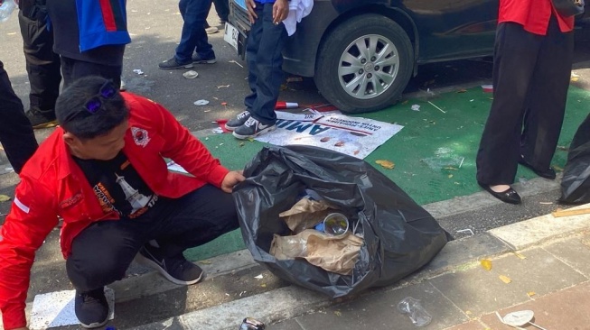 Relawan pasangan Ganjar-Mahfud gelar operasi semut berupa memungut sampah yang berserakan di depan kantor KPU RI, Jakarta Pusat, Kamis (19/10/2023) sore. [Suara.com/Rakha]