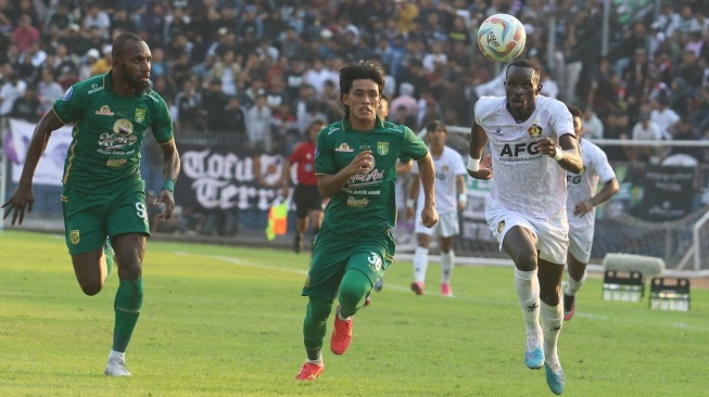 Pesepak bola Persik Kediri Flavio Silva (kanan) berebut bola dengan pesepak bola Persebaya Surabaya Ripal Wahyudi (tengah) dalam pertandingan kompetisi Liga 1 di Stadion Brawijaya, Kota Kediri, Jawa Timur, Jumat (27/10/2023). Persik Kediri menang dengan skor 4-0. ANTARA FOTO/Prasetia Fauzani/nym. 