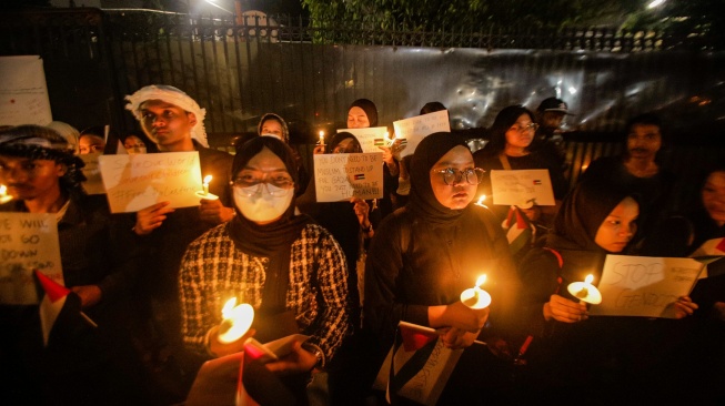 Sejumlah elemen masyarakat menyalakan lilin saat mengikuti aksi damai Bela Palestina di Kedutaan Besar Palestina, Jakarta, Kamis (2/11/2023). [Suara.com/Alfian Winanto]