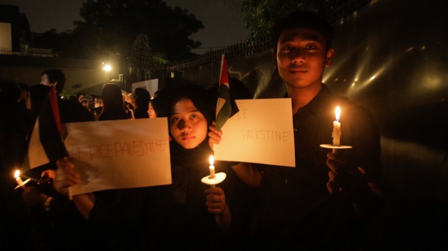 Sejumlah elemen masyarakat menyalakan lilin saat mengikuti aksi damai Bela Palestina di Kedutaan Besar Palestina, Jakarta, Kamis (2/11/2023). [Suara.com/Alfian Winanto]