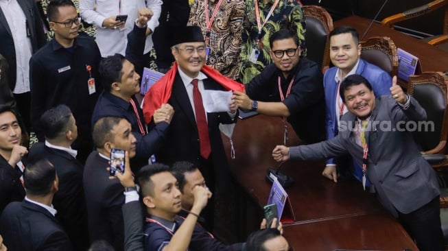 Ketua Majelis Kehormatan Mahkamah Konstitusi (MKMK) Jimly Asshiddiqie (tengah) dikalungi bendera merah putih oleh para pelapor usai sidang putusan etik di Gedung MK, Jakarta, Selasa (7/11/2023). [Suara.com/Alfian Winanto]